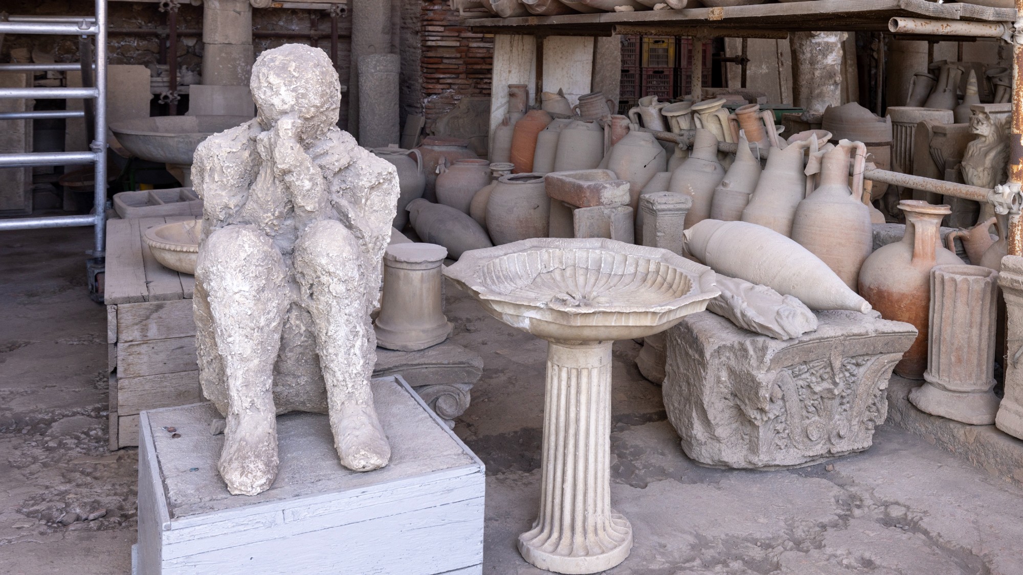 Plaster cast of human body alongside ancient pots and other artefacts at Pompeii
