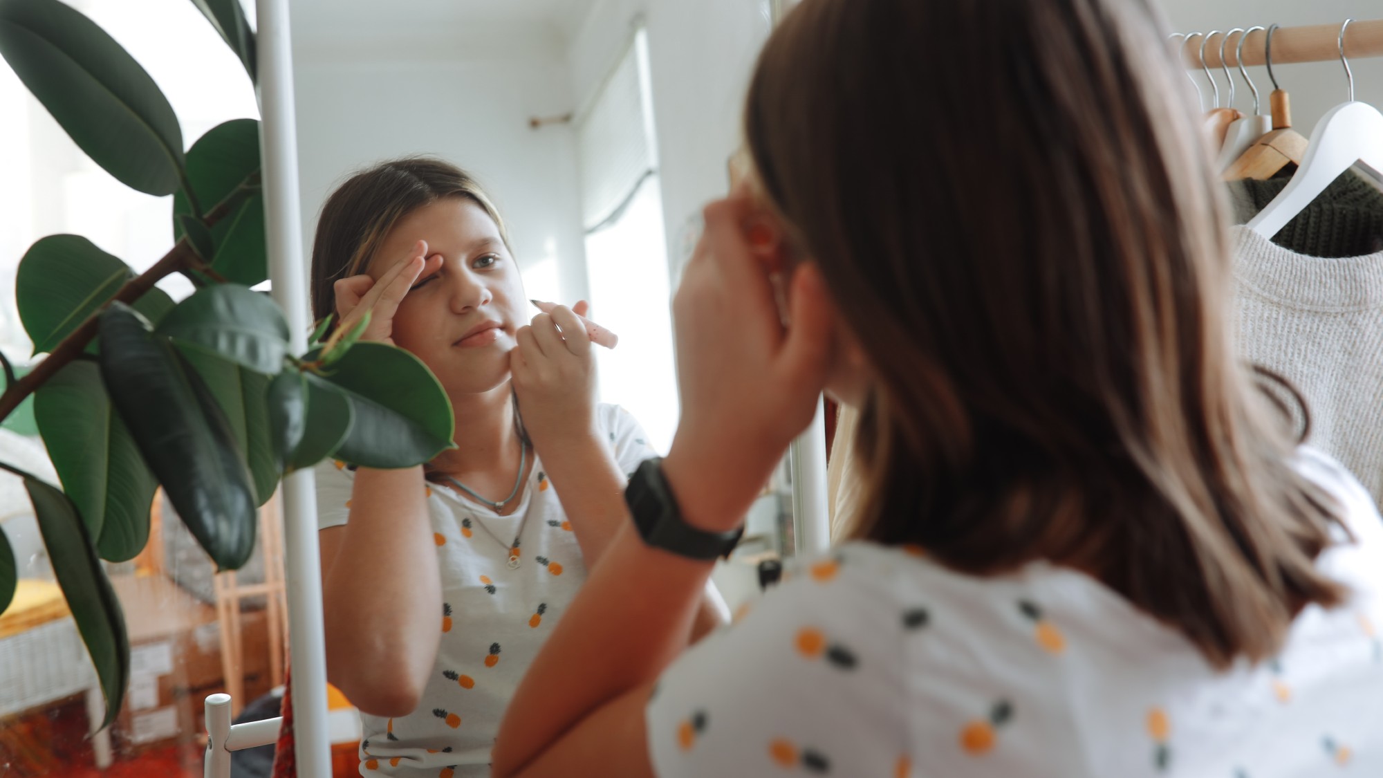A girl applies a beauty product in front of a mirror