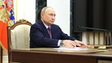 Russian President Vladimir Putin seated at a table 