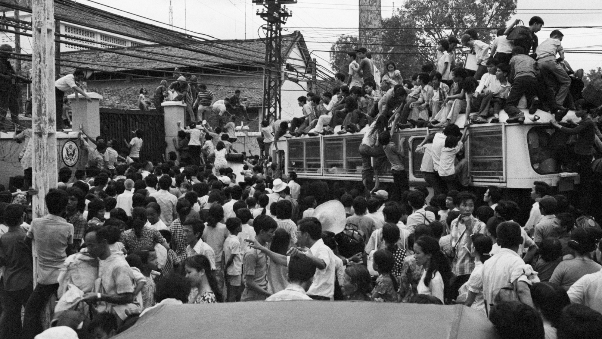 Vietnamese civilians climbing on board a US bus, trying to get into the US embassy to join the American evacuation from Saigon