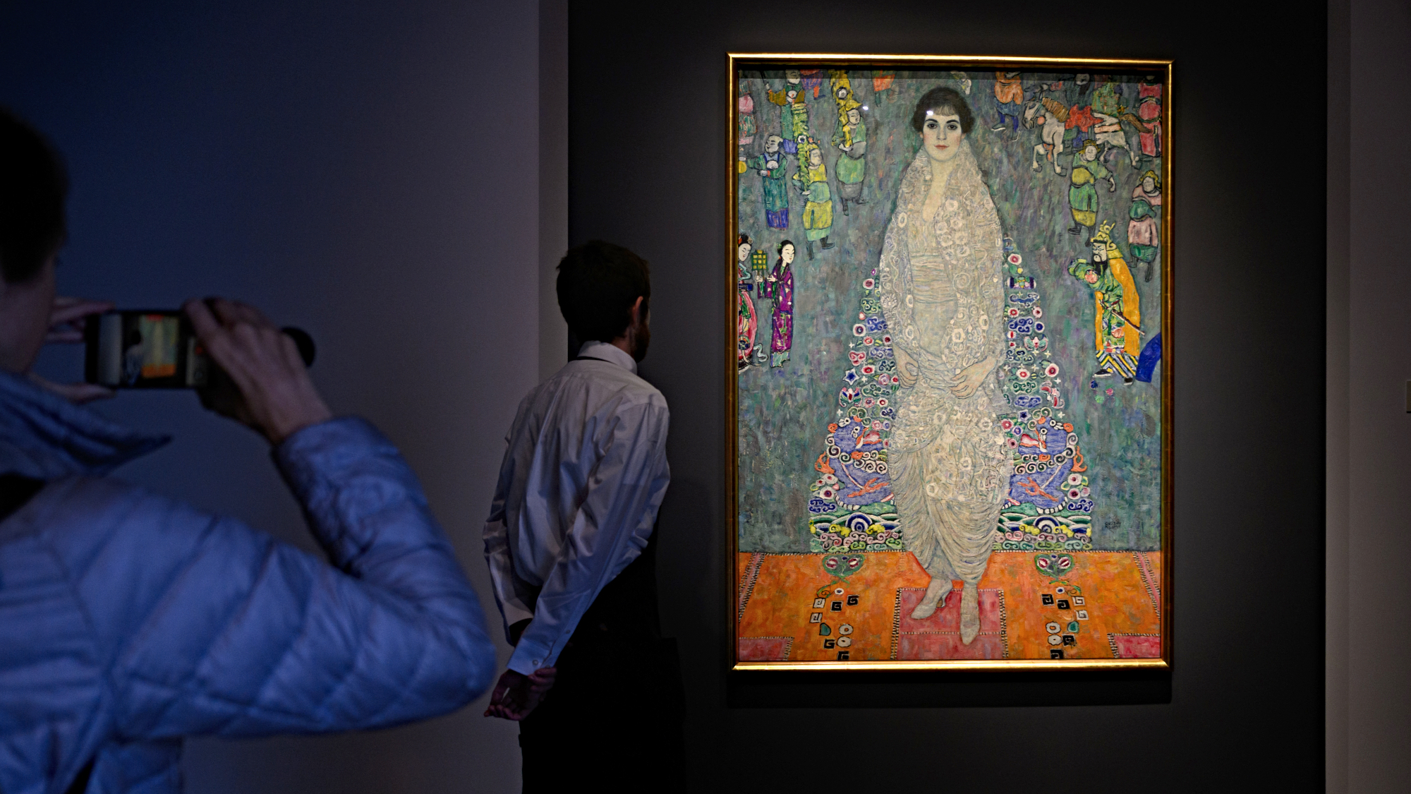 Hands holding a phone take a photo of The Portrait of Elisabeth Lederer by Gustav Klimt on view at Sotheby's New York