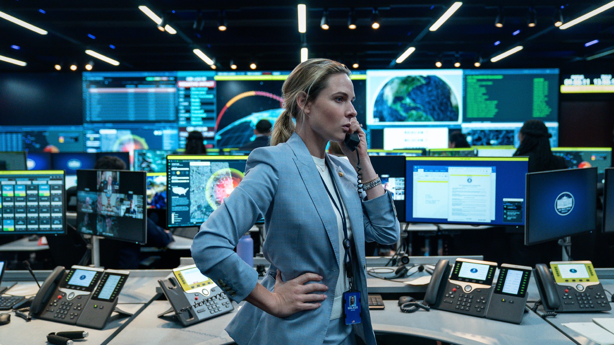 direct profile shot of Rebecca Ferguson in a blue suit on the phone in what looks like a war room. a still from the movie "A House of Dynamite"