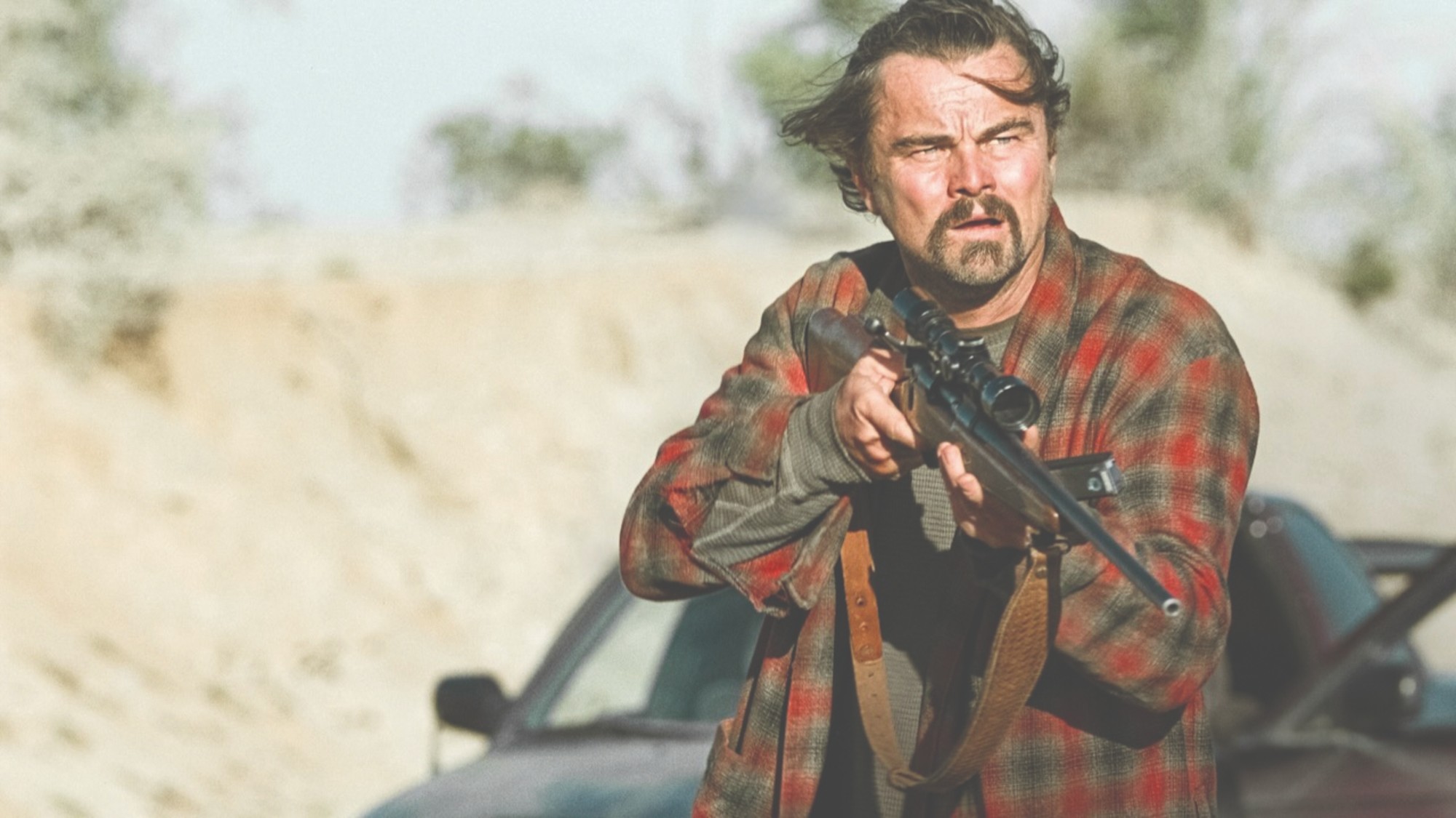 Leonardo DiCaprio holds a rifle