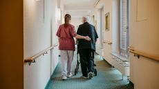 A stock photo of a nurse assisting a woman with a walker. 